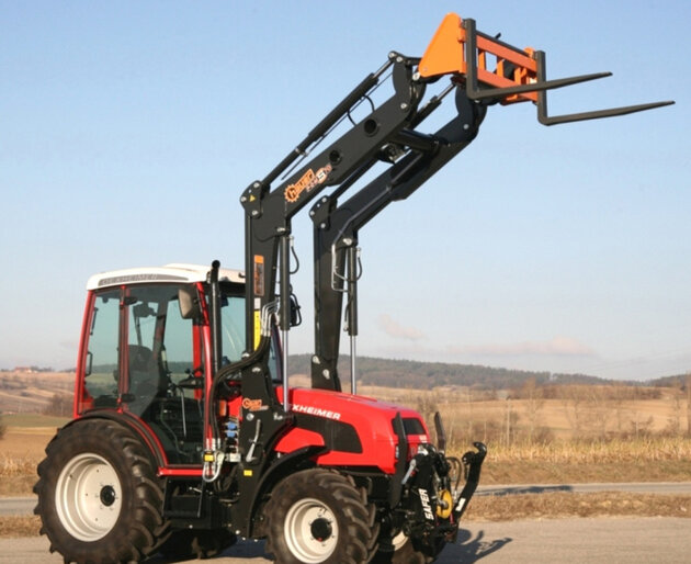 Traktor mit angehobener Lastgabel auf Feldweg