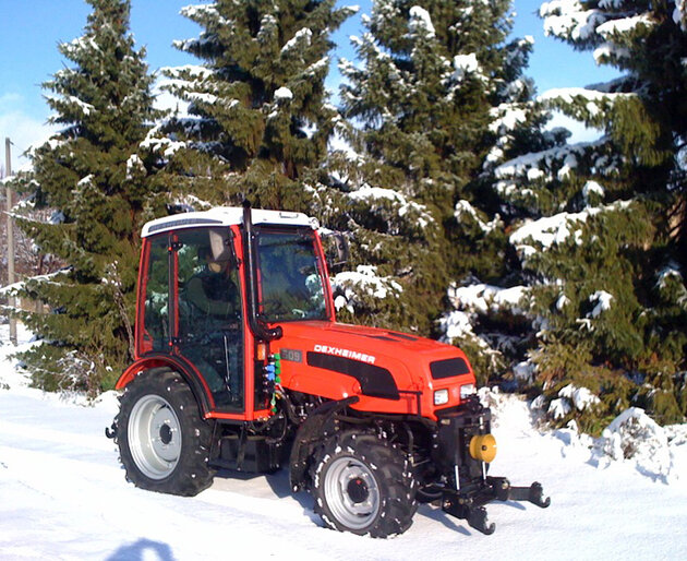 Traktor mit Schneeketten im verschneiten Waldgebiet